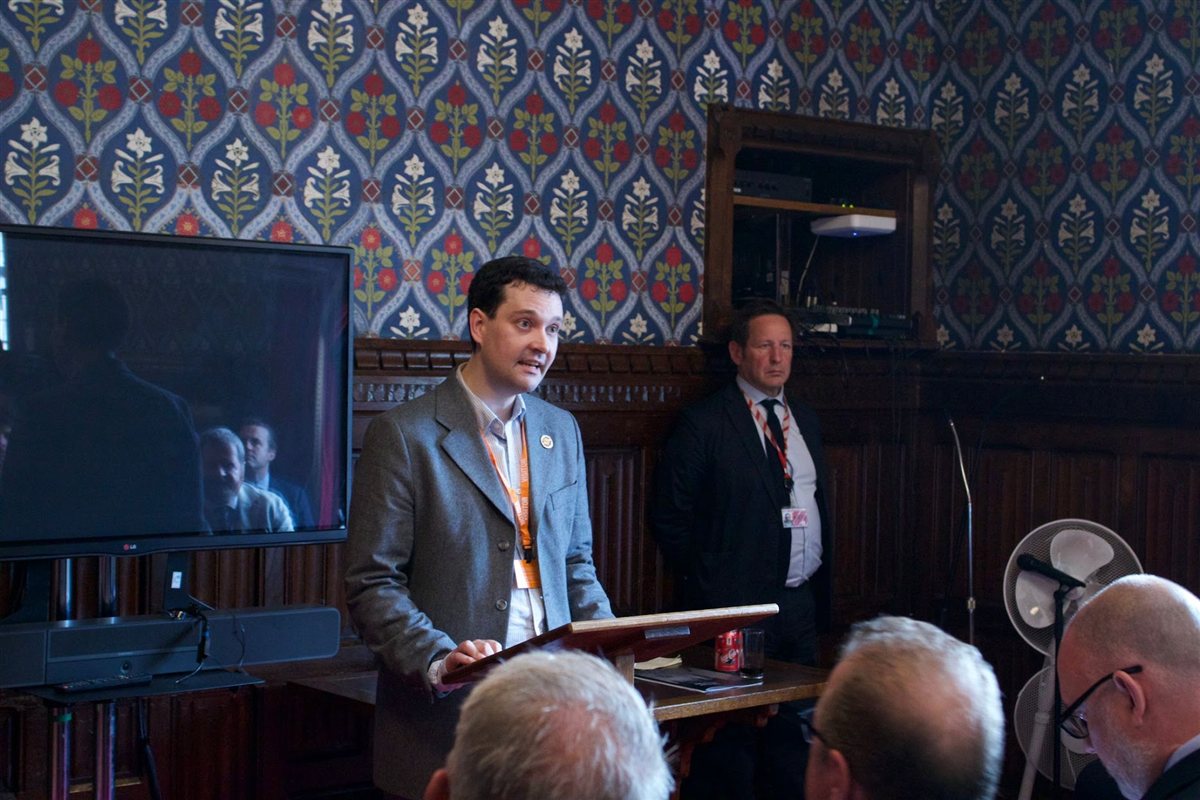 Speaker addressing delegates in a House of Commons meeting room